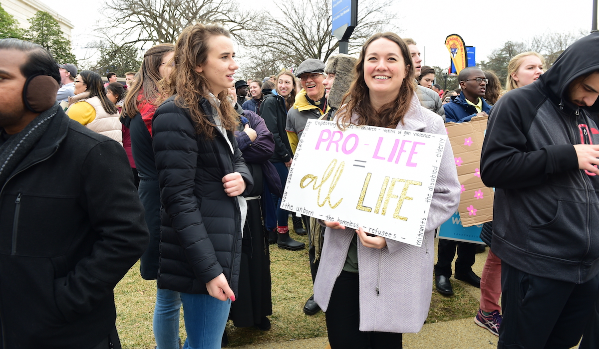 student smiles and holds pro life sign at the march for life