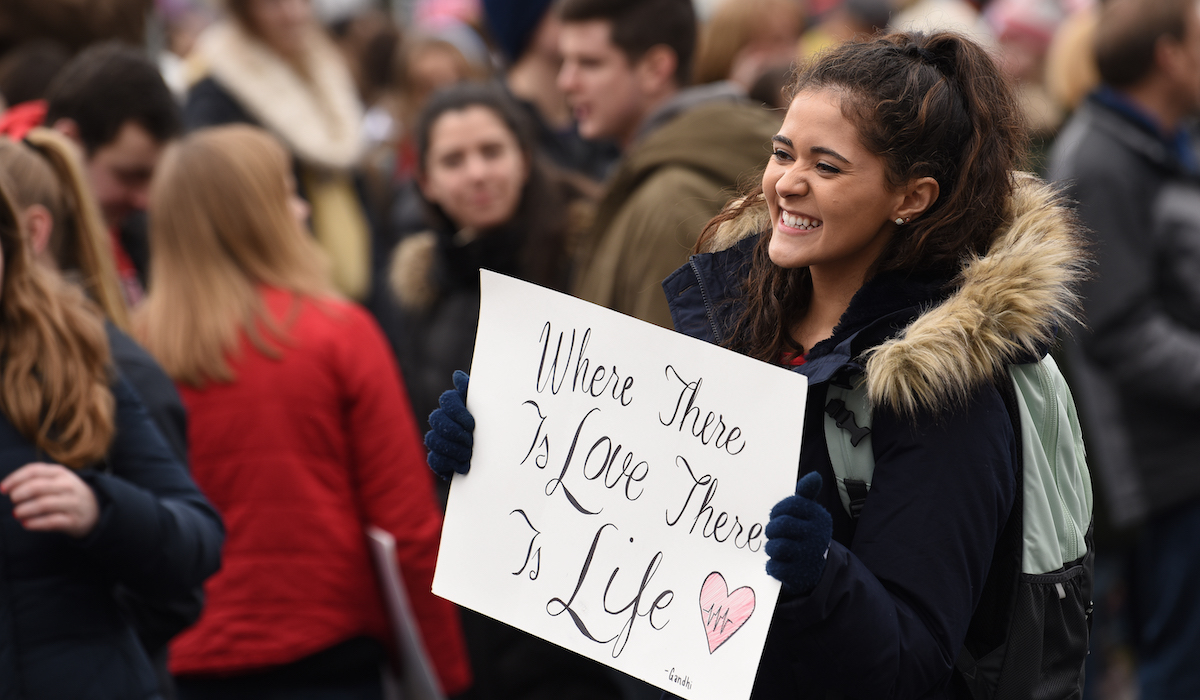 student smiles and holds a sign at the march for life