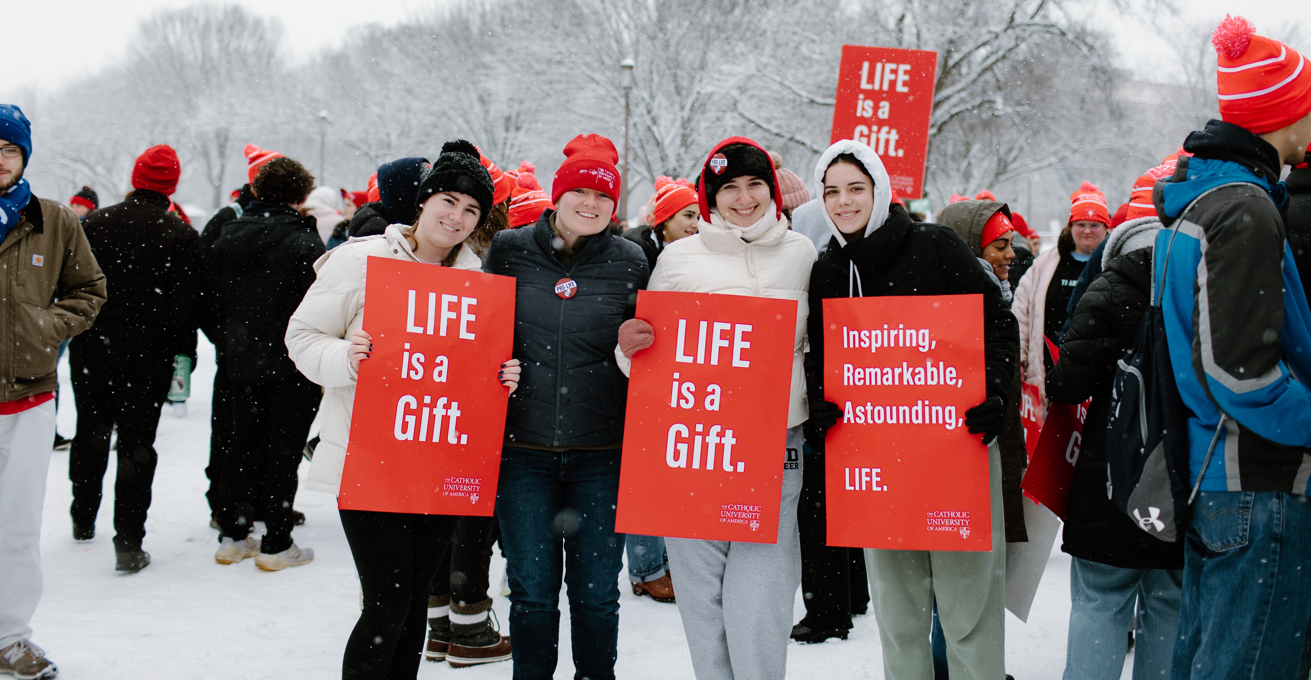 student smiles and holds pro life sign at the march for life