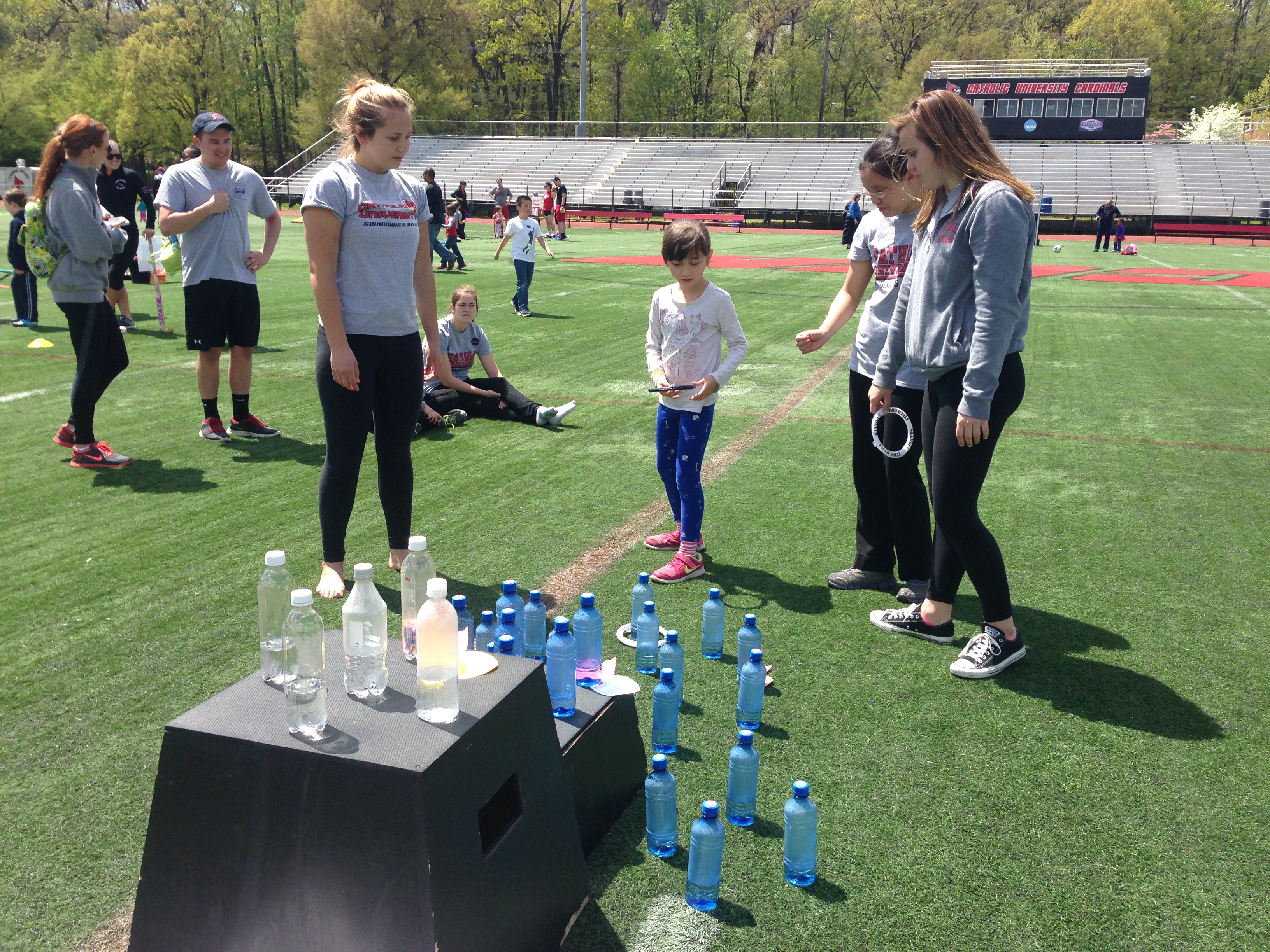 Picture of girl playing ring toss in plastic bottles with CUA students